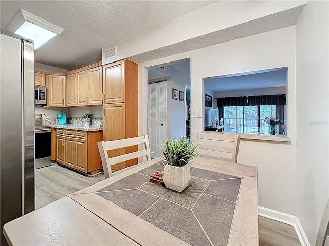 1207 Pine Ridge Cir W Unit H2, Tarpon Springs, FL 34688 - dining space featuring light wood-style floors and a textured ceiling