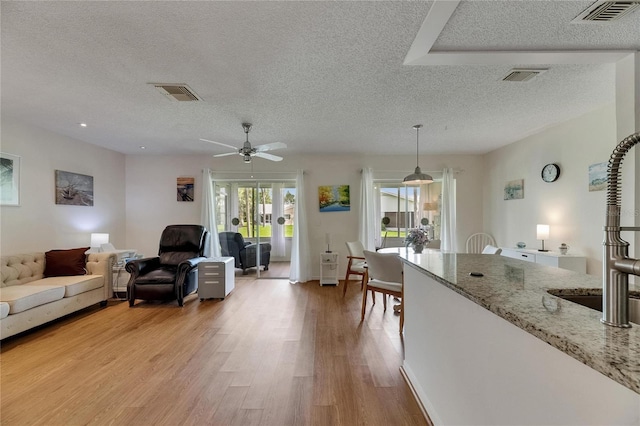 123 Glendower Cir Unit 123, Sun City Center, FL 33573 - living room featuring a textured ceiling, light wood finished floors, and a ceiling fan