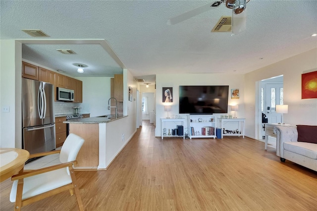 123 Glendower Cir Unit 123, Sun City Center, FL 33573 - kitchen with appliances with stainless steel finishes, open floor plan, light wood-style flooring, a peninsula, and brown cabinetry