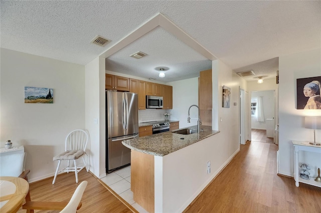 123 Glendower Cir Unit 123, Sun City Center, FL 33573 - kitchen with appliances with stainless steel finishes, decorative backsplash, light stone counters, a textured ceiling, and brown cabinets