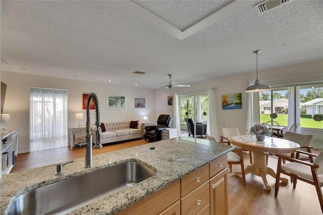 123 Glendower Cir Unit 123, Sun City Center, FL 33573 - kitchen with a textured ceiling, light wood-type flooring, open floor plan, light stone counters, and a ceiling fan