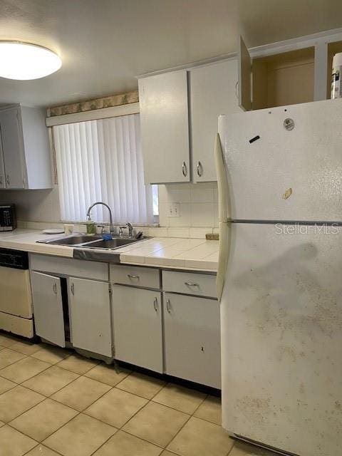 8636 Tahoe Ct Unit 13, Tampa, FL 33614 - kitchen featuring freestanding refrigerator, dishwasher, tile counters, light tile patterned floors, and backsplash