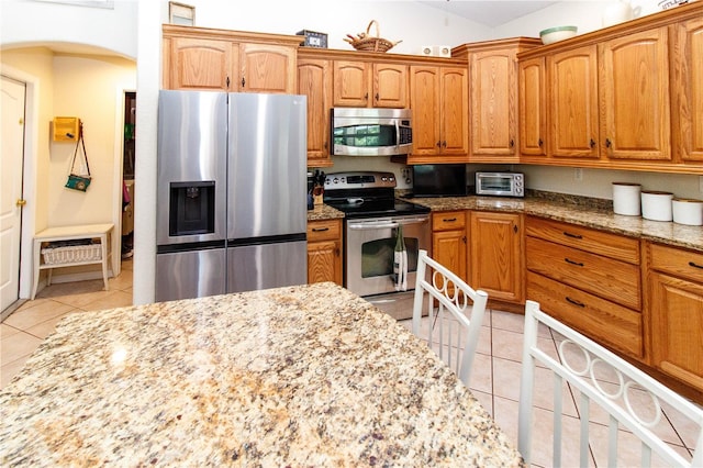 11945 Darwin Ave, New Port Richey, FL 34654 - kitchen with stainless steel appliances, light tile patterned floors, light stone countertops, and arched walkways