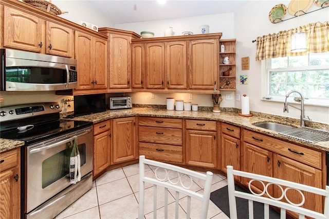 11945 Darwin Ave, New Port Richey, FL 34654 - kitchen featuring appliances with stainless steel finishes, light tile patterned flooring, light stone countertops, and brown cabinets