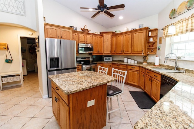 11945 Darwin Ave, New Port Richey, FL 34654 - kitchen featuring appliances with stainless steel finishes, a center island, light stone countertops, light tile patterned floors, and a ceiling fan