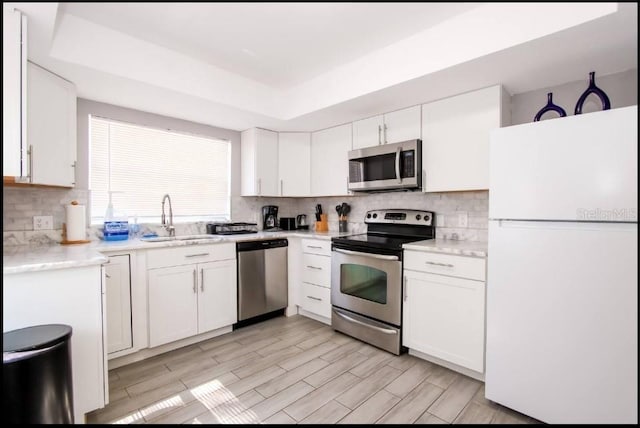 1004 Osage St, Clearwater, FL 33755 - kitchen with appliances with stainless steel finishes, light countertops, a tray ceiling, and white cabinetry