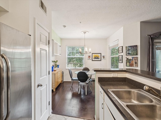 2010 E Palm Ave Unit 14303, Tampa, FL 33605 - kitchen with stainless steel fridge, dark countertops, white cabinets, a chandelier, and hardwood / wood-style floors