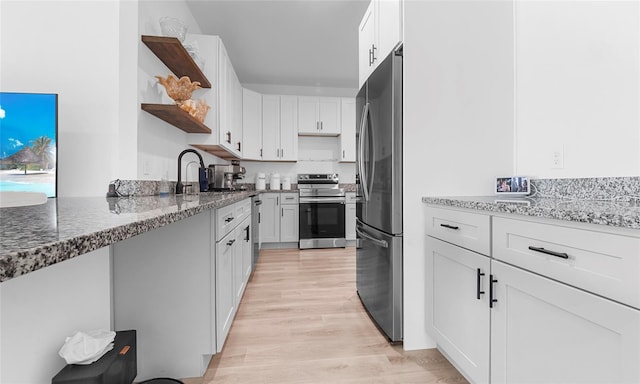 9429 Northcliffe Blvd, Spring Hill, FL 34606 - kitchen with appliances with stainless steel finishes, open shelves, dark stone counters, light wood finished floors, and white cabinetry