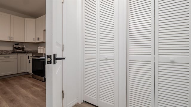 9429 Northcliffe Blvd, Spring Hill, FL 34606 - kitchen with stainless steel electric range, light wood-style floors, dark stone counters, and white cabinets