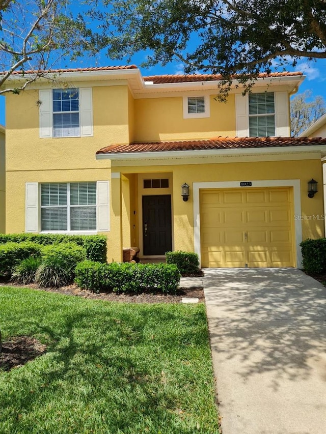 8923 Cuban Palm Rd, Kissimmee, FL 34747 - view of front facade featuring a tiled roof, concrete driveway, stucco siding, a garage, and a front lawn