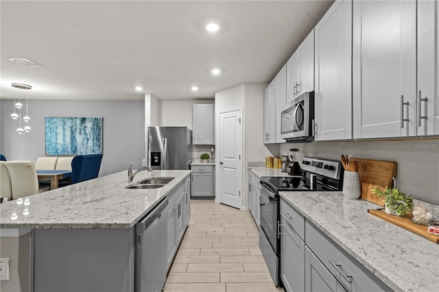 12277 Spring Hill Dr, Spring Hill, FL 34609 - kitchen with stainless steel appliances, gray cabinets, light stone counters, recessed lighting, and a center island with sink