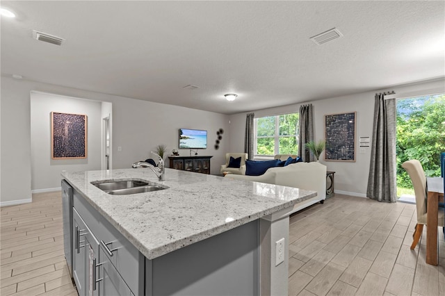 12277 Spring Hill Dr, Spring Hill, FL 34609 - kitchen featuring gray cabinetry, wood finish floors, open floor plan, a kitchen island with sink, and light stone countertops