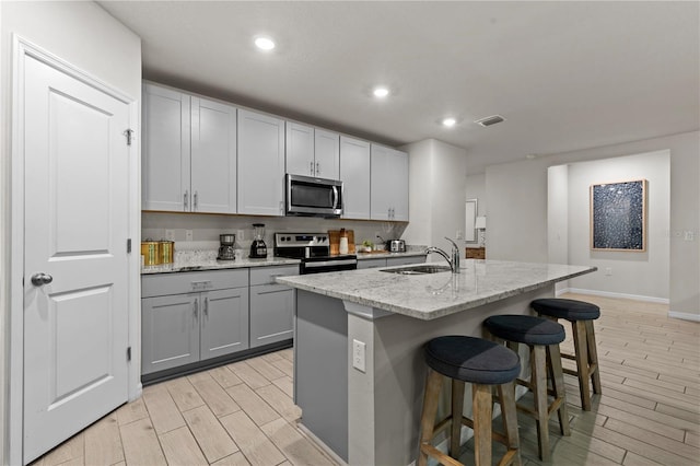 12277 Spring Hill Dr, Spring Hill, FL 34609 - kitchen featuring stainless steel appliances, gray cabinets, wood tiled floors, recessed lighting, and a kitchen breakfast bar