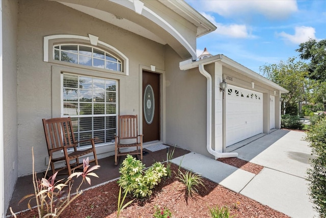 27826 Sora Blvd, Wesley Chapel, FL 33544 - property entrance with stucco siding, a garage, and concrete driveway