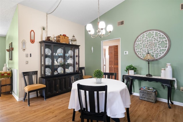 7022 Kingsway Dr, Port Richey, FL 34668 - dining area with a chandelier, light wood-type flooring, and high vaulted ceiling