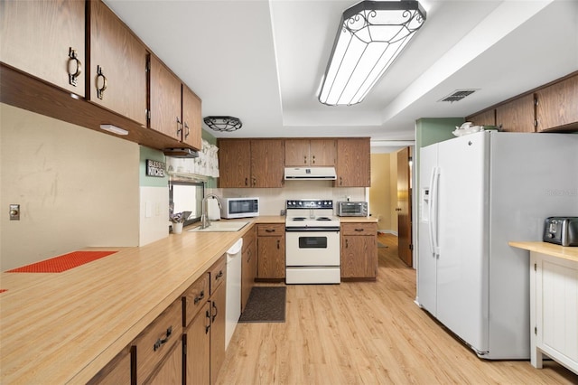 7022 Kingsway Dr, Port Richey, FL 34668 - kitchen with white appliances, light wood-type flooring, under cabinet range hood, light countertops, and brown cabinets