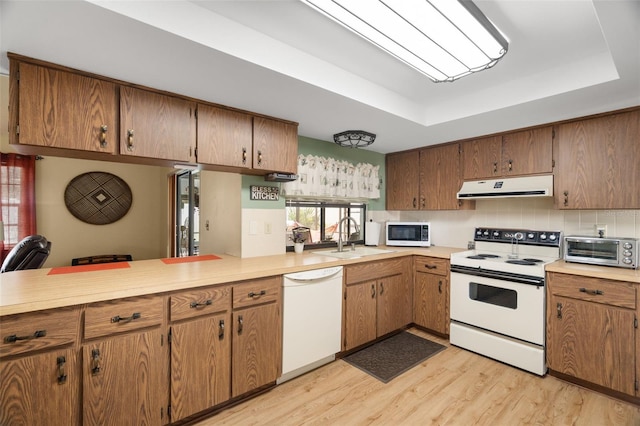 7022 Kingsway Dr, Port Richey, FL 34668 - kitchen with white appliances, ventilation hood, a raised ceiling, light wood finished floors, and light countertops