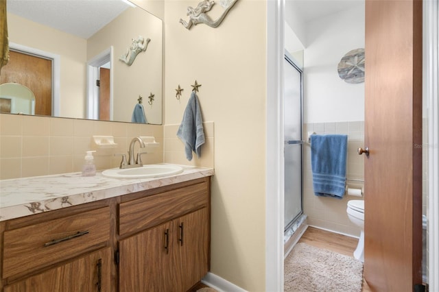 7022 Kingsway Dr, Port Richey, FL 34668 - full bathroom featuring tile walls, vanity, a stall shower, and wood finished floors