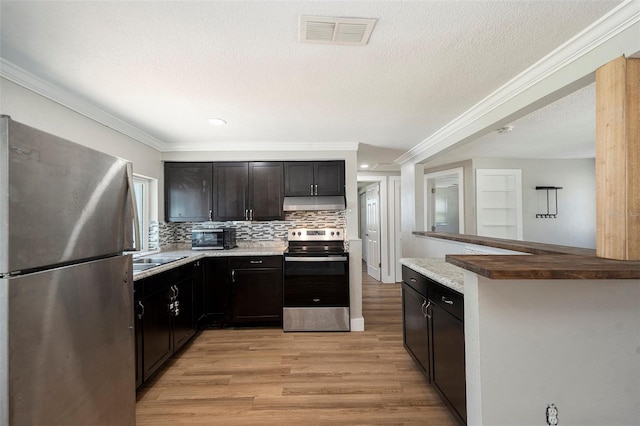 3509 Brookston Dr, Holiday, FL 34691 - kitchen with stainless steel appliances, under cabinet range hood, light wood-type flooring, ornamental molding, and decorative backsplash