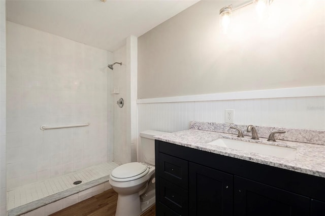 3509 Brookston Dr, Holiday, FL 34691 - bathroom featuring vanity, a tile shower, wood finished floors, and wainscoting