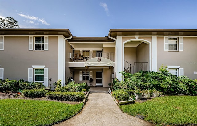 5265 E Bay Dr Unit 521, Clearwater, FL 33764 - view of front facade with stucco siding, a balcony, and a front lawn
