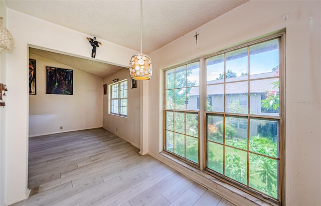 5265 E Bay Dr Unit 521, Clearwater, FL 33764 - unfurnished dining area with a textured ceiling, light wood finished floors, and vaulted ceiling