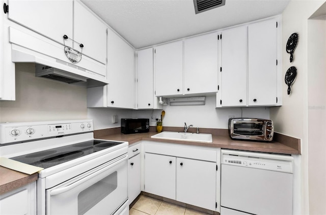2700 Bayshore Blvd Unit 1206, Dunedin, FL 34698 - kitchen featuring white appliances, under cabinet range hood, white cabinetry, and light tile patterned floors