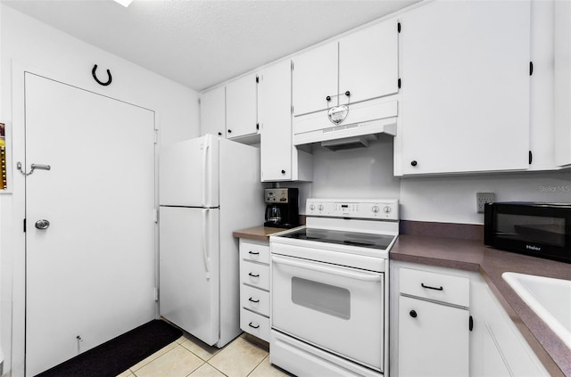 2700 Bayshore Blvd Unit 1206, Dunedin, FL 34698 - kitchen with white appliances, custom exhaust hood, light tile patterned flooring, white cabinetry, and dark countertops