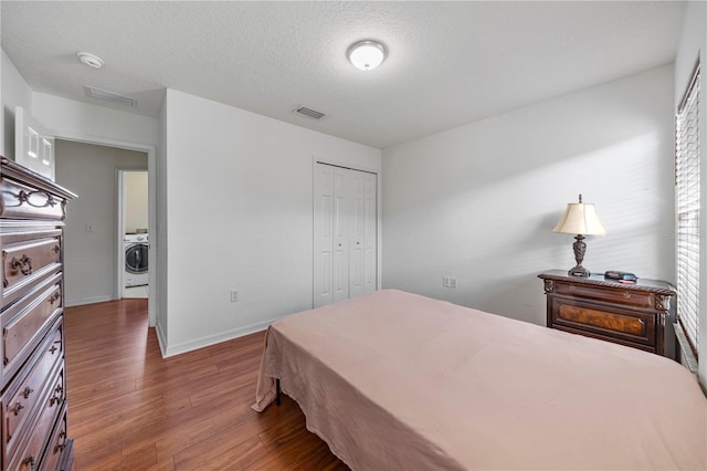 7819 Carriage Pointe Dr, Gibsonton, FL 33534 - bedroom featuring washer / clothes dryer, wood finished floors, a closet, and a textured ceiling