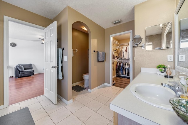 7819 Carriage Pointe Dr, Gibsonton, FL 33534 - bathroom featuring vanity, a walk in closet, tile patterned flooring, a textured ceiling, and a ceiling fan