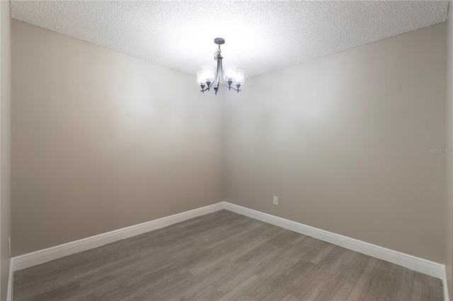 3805 Cortez Cir Unit B, Tampa, FL 33614 - spare room featuring light wood-style flooring, a chandelier, and a textured ceiling