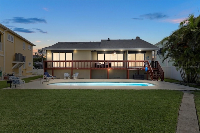 17025 Dolphin Dr, North Redington Beach, FL 33708 - back of property at dusk with stairs, a wooden deck, an outdoor pool, and a patio