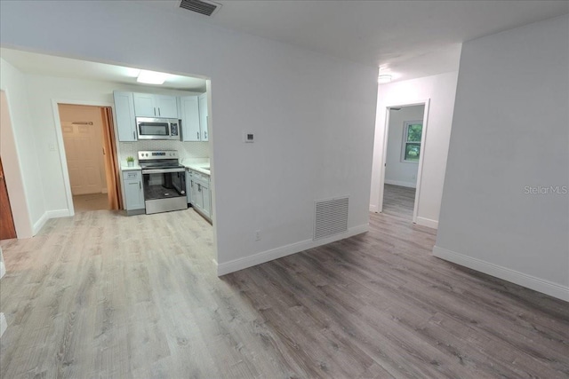 1400 E Fern Rd, Lakeland, FL 33801 - kitchen with appliances with stainless steel finishes, light wood-style flooring, light countertops, and backsplash