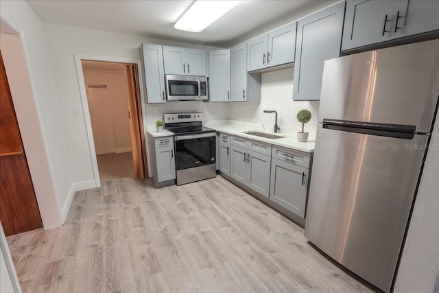 1400 E Fern Rd, Lakeland, FL 33801 - kitchen featuring appliances with stainless steel finishes, gray cabinetry, light countertops, light wood-style floors, and tasteful backsplash