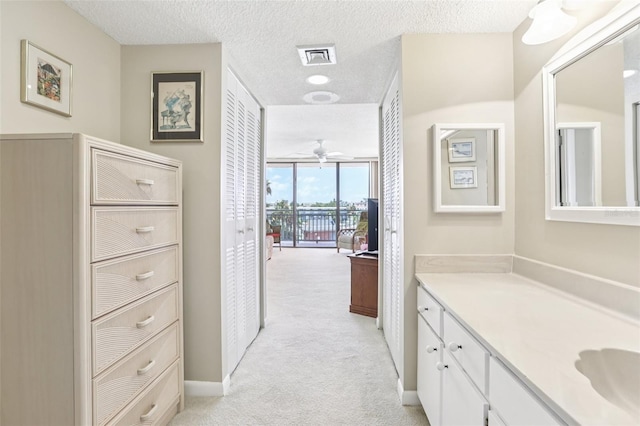 1 Key Capri Unit 302E, Treasure Island, FL 33706 - bathroom featuring vanity, a textured ceiling, expansive windows, and ceiling fan