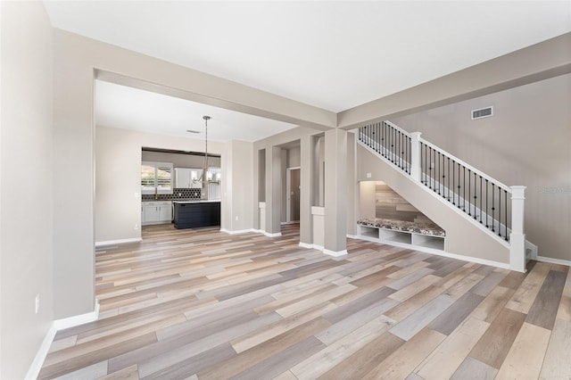 1291 Blackrush Dr, Tarpon Springs, FL 34689 - unfurnished living room featuring stairs, light wood-style floors, and a chandelier