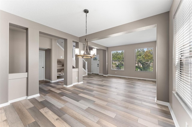 1291 Blackrush Dr, Tarpon Springs, FL 34689 - unfurnished dining area with stairs, a chandelier, and light wood-style flooring