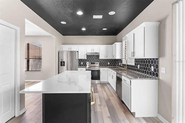 1291 Blackrush Dr, Tarpon Springs, FL 34689 - kitchen with appliances with stainless steel finishes, a kitchen island, light stone counters, light wood-type flooring, and recessed lighting