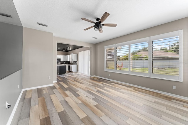 1291 Blackrush Dr, Tarpon Springs, FL 34689 - unfurnished living room with light wood finished floors, ceiling fan, and a textured ceiling