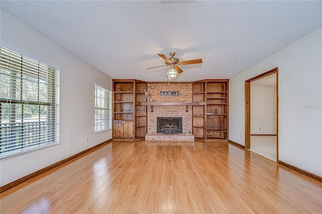 3125 S Miller Rd, Valrico, FL 33596 - unfurnished living room featuring ceiling fan, light wood finished floors, a textured ceiling, a fireplace, and built in features