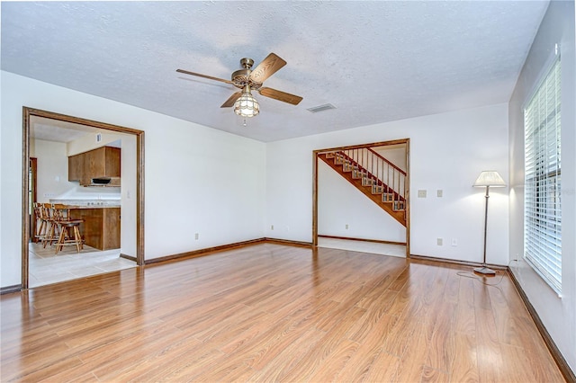 3125 S Miller Rd, Valrico, FL 33596 - unfurnished living room featuring a ceiling fan, stairway, wood finished floors, plenty of natural light, and a textured ceiling