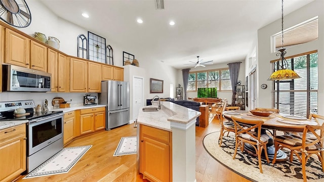 3506 Cordgrass Dr, Valrico, FL 33596 - kitchen with appliances with stainless steel finishes, a kitchen island with sink, light wood-style flooring, a ceiling fan, and open floor plan