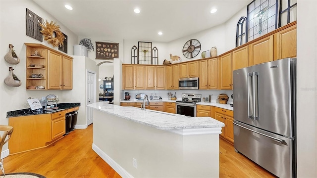 3506 Cordgrass Dr, Valrico, FL 33596 - kitchen featuring stainless steel appliances, open shelves, a towering ceiling, a kitchen island with sink, and light wood-style floors