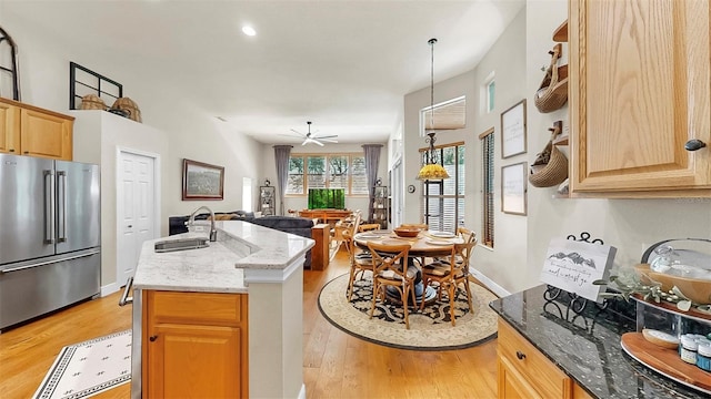 3506 Cordgrass Dr, Valrico, FL 33596 - kitchen featuring high quality fridge, light wood-style flooring, open floor plan, light stone countertops, and an island with sink