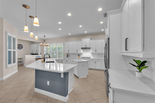 6207 Bleeker St, Riverview, FL 33578 - kitchen with an island with sink, light tile patterned floors, white cabinetry, a chandelier, and backsplash