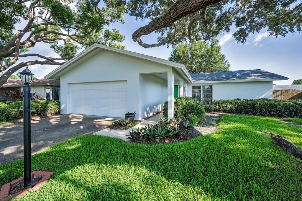 2559 Redwood Cir, Clearwater, FL 33763 - single story home with stucco siding, an attached garage, driveway, and a front lawn
