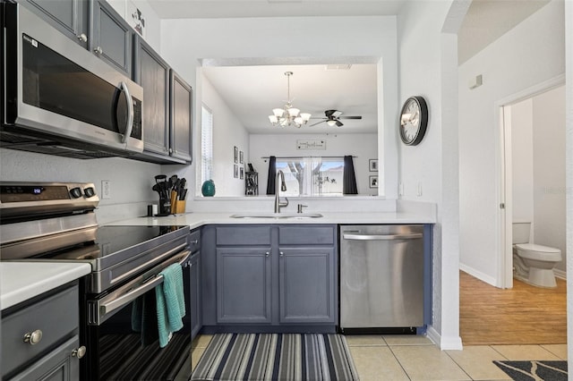 1052 Calabria Ave, Davenport, FL 33897 - kitchen with stainless steel appliances, light tile patterned floors, a chandelier, light countertops, and hanging light fixtures