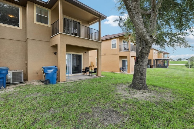 1052 Calabria Ave, Davenport, FL 33897 - rear view of house featuring stucco siding, a balcony, a patio, and a lawn