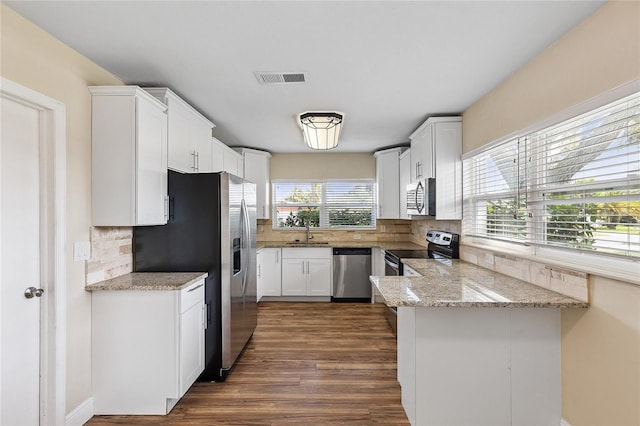 10502 Orange Blossom Ln, Seminole, FL 33772 - kitchen with stainless steel appliances, backsplash, white cabinetry, and dark wood finished floors