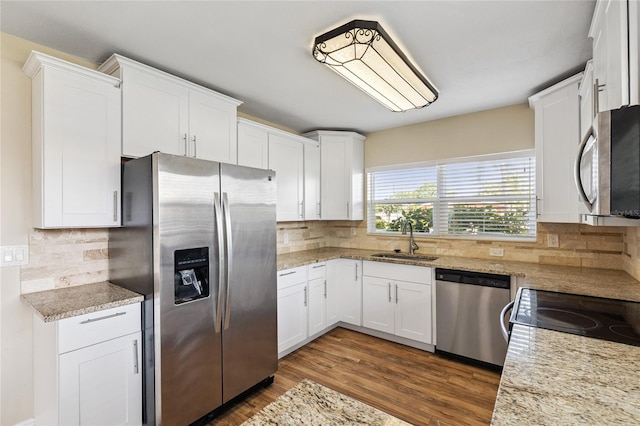 10502 Orange Blossom Ln, Seminole, FL 33772 - kitchen with stainless steel appliances, white cabinetry, wood finished floors, and tasteful backsplash